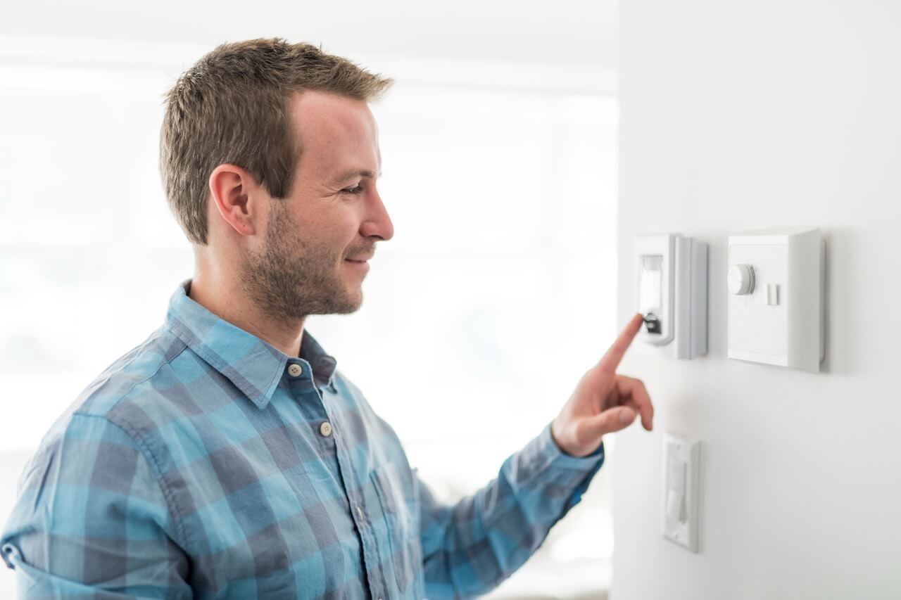 Man wearing collared shirt adjusting thermostat